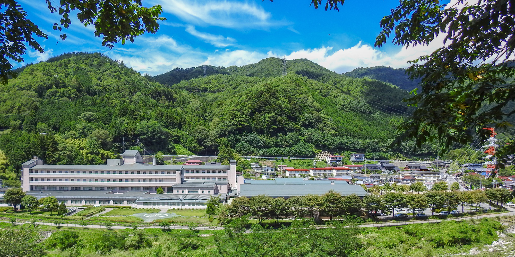 山々に囲まれた介護施設の外観。広大な敷地に複数棟の建物が配置されている。